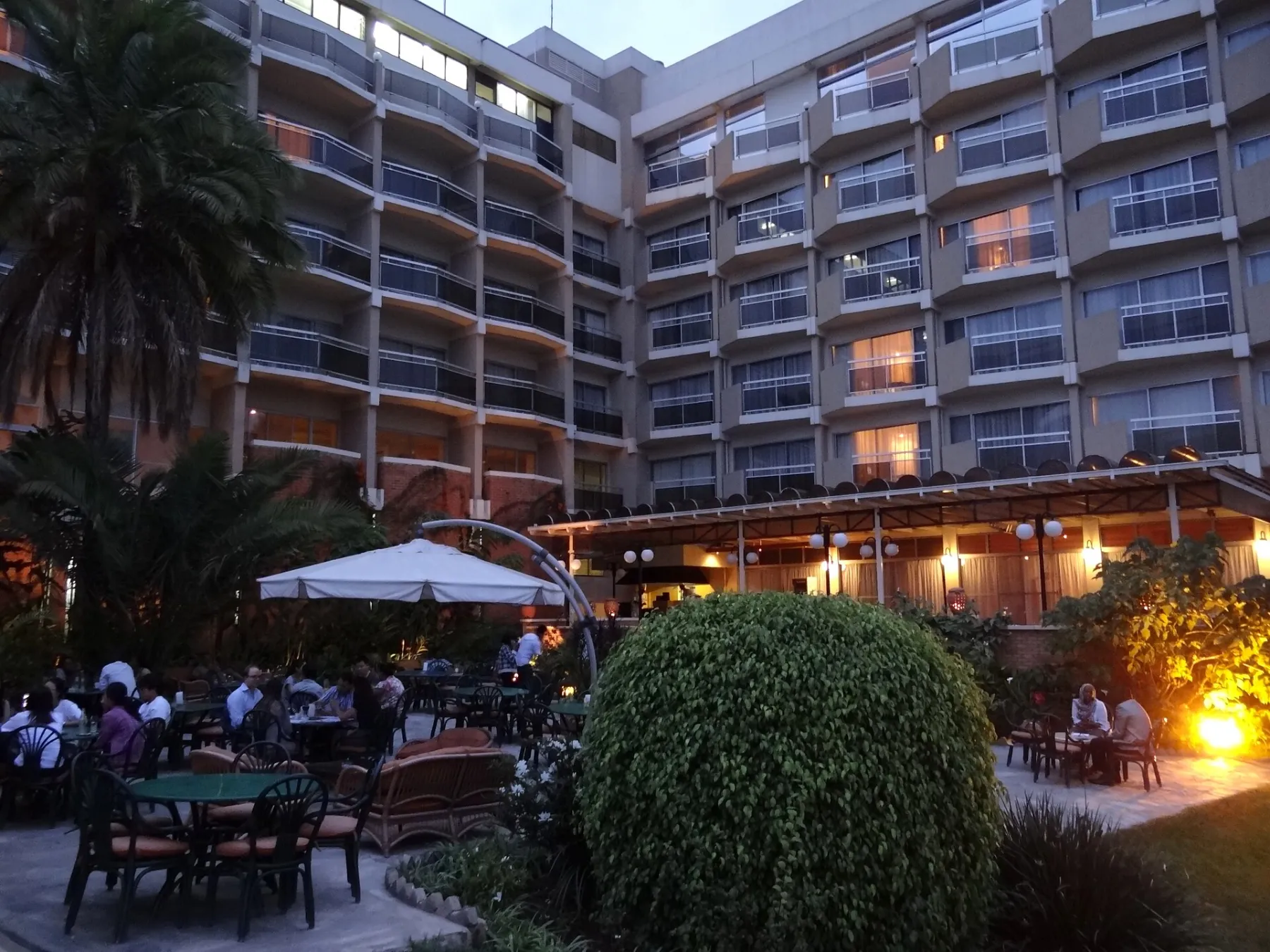 Guests at garden tables of a hotel bar in Kigali at dusk