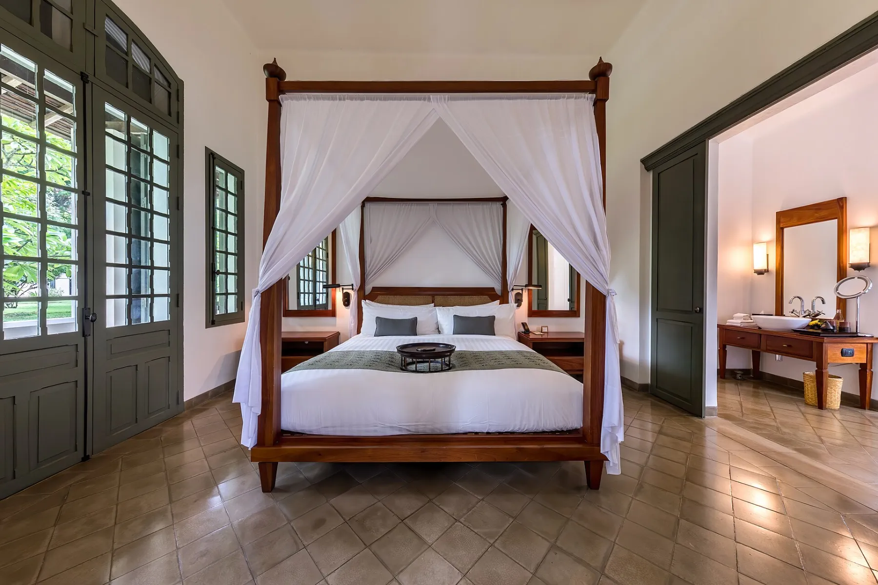 A canopy bed in a calm, white luxury hotel suite