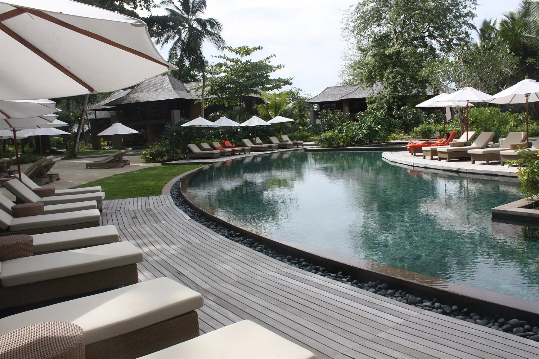 A resort pool with sun loungers and timber decking